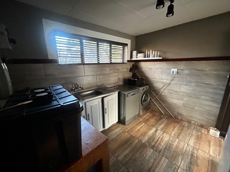 A functional laundry room featuring tiled wall cladding, built-in cabinetry with a stainless steel sink, and tiled flooring.