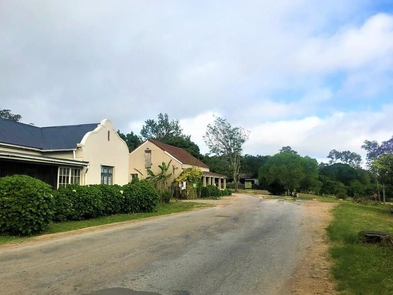 A street view showing the exterior facade of a property with a gabled roof and veranda, situated along a rural road.