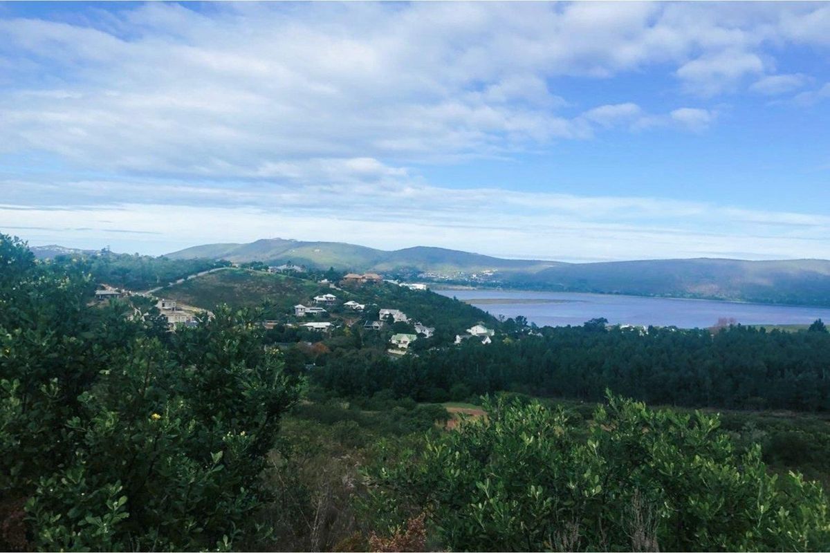 A scenic elevated view overlooking a coastal landscape, surrounding hills, and a body of water, showcasing the natural beauty of the area.