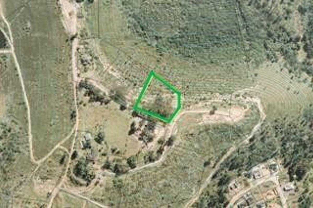An aerial view of a vacant residential plot of land, highlighting the property boundaries and surrounding landscape.