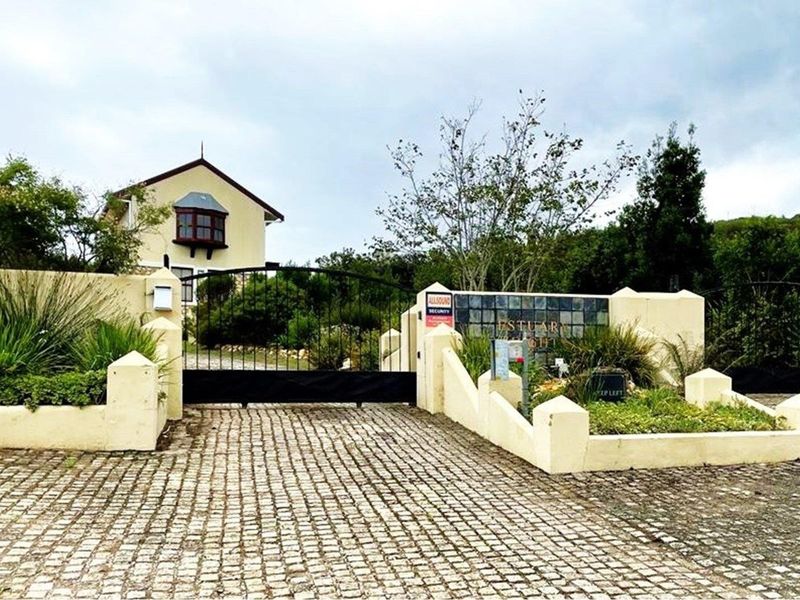 Front entrance view of the residential property featuring a cobblestone driveway, secure wrought iron gate, and masonry boundary wall.