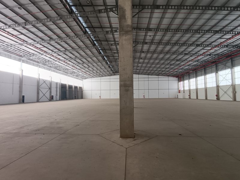 A large, open-plan industrial warehouse space featuring high ceilings, concrete flooring, and exposed steel structural elements, suitable for storage or manufacturing operations.