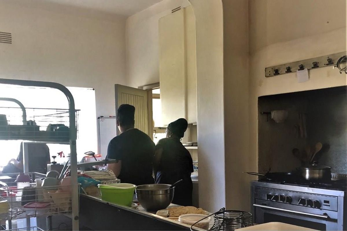 A functional commercial kitchen space featuring a built-in oven, cooktop, and extractor fan with existing cabinetry and ventilation infrastructure.