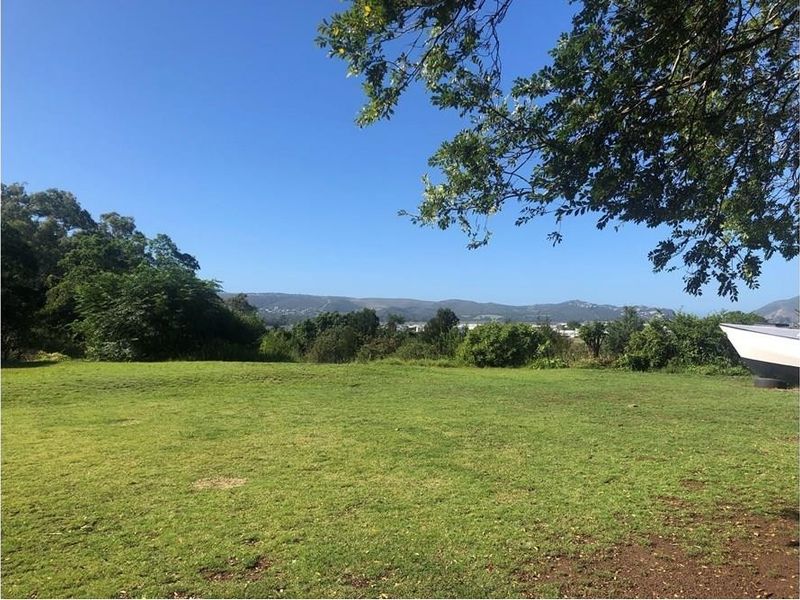 A spacious, open garden area featuring a well-maintained lawn and mature trees, offering a scenic view of the surrounding landscape.