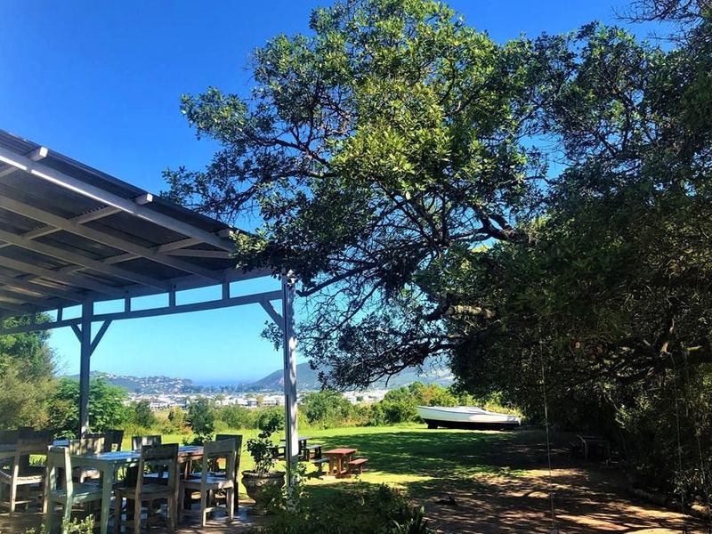 A covered outdoor patio area overlooking a spacious garden with mature trees and scenic distant views.