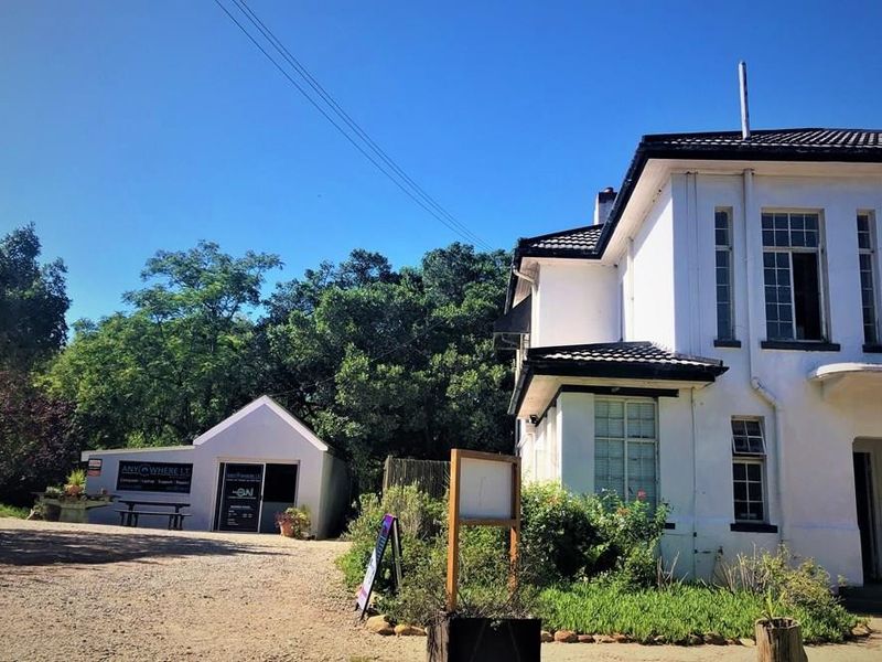 Front exterior view of a commercial property featuring a gravel driveway, white painted facade, and multi-pane windows.