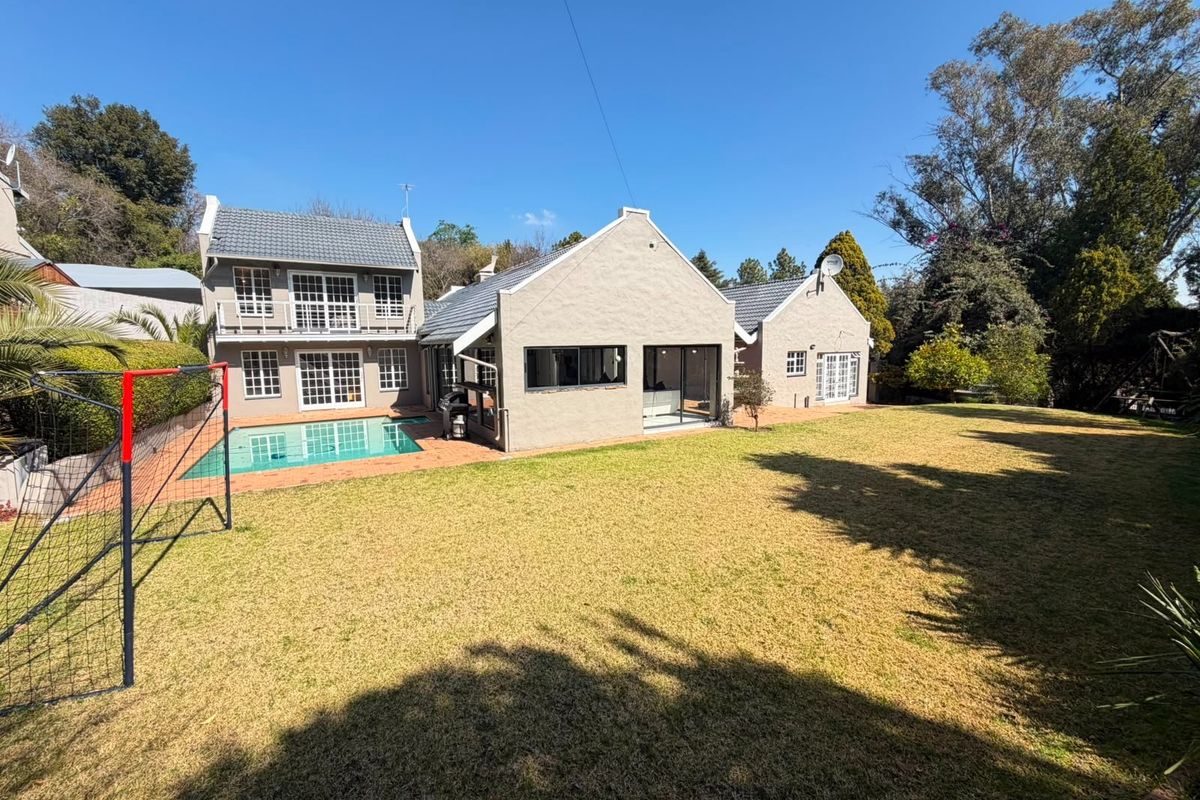 Rear view of the property featuring a swimming pool, landscaped garden, and a multi-level exterior with balcony and sliding door access.