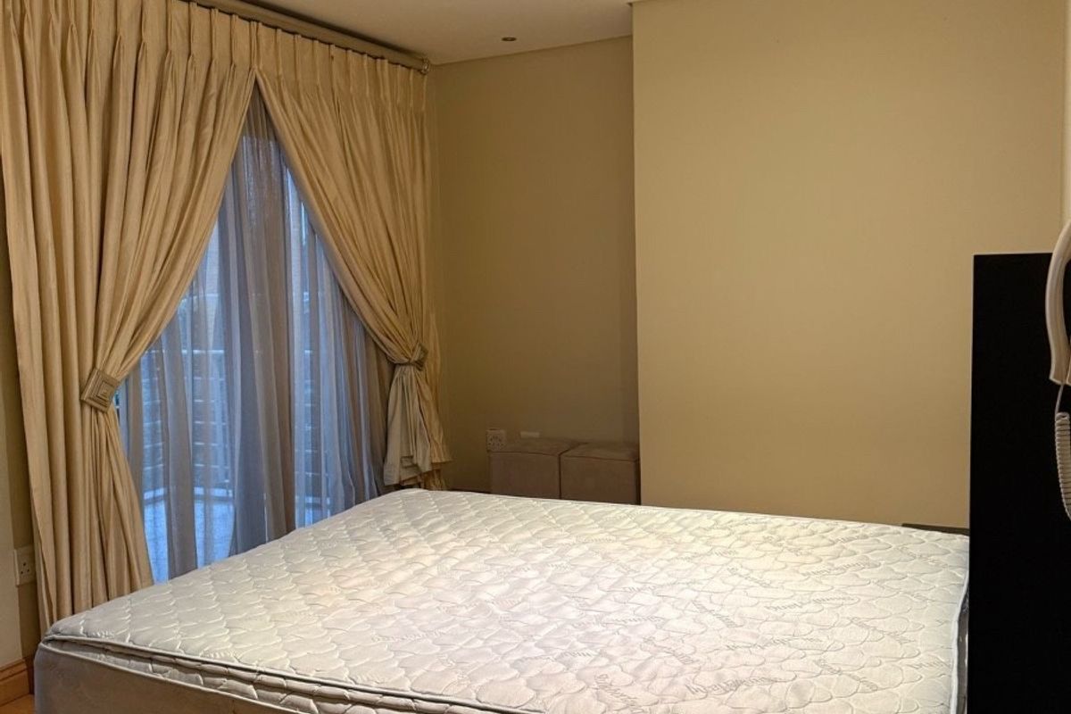 A well-lit bedroom featuring hardwood flooring, recessed ceiling downlights, and floor-to-ceiling curtains covering a large window or balcony door.