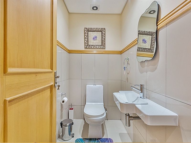 A compact, well-maintained guest bathroom featuring tiled walls, a wall-mounted basin, and a modern toilet.