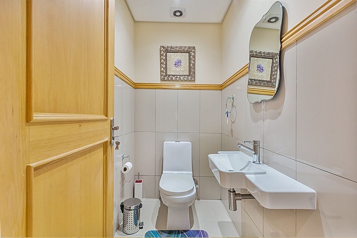 A compact, well-maintained guest bathroom featuring tiled walls, a wall-mounted basin, and a modern toilet.