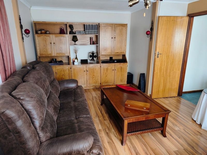 A living room featuring built-in wooden cabinetry, laminate flooring, and a classic wooden door, offering a functional and traditional layout.