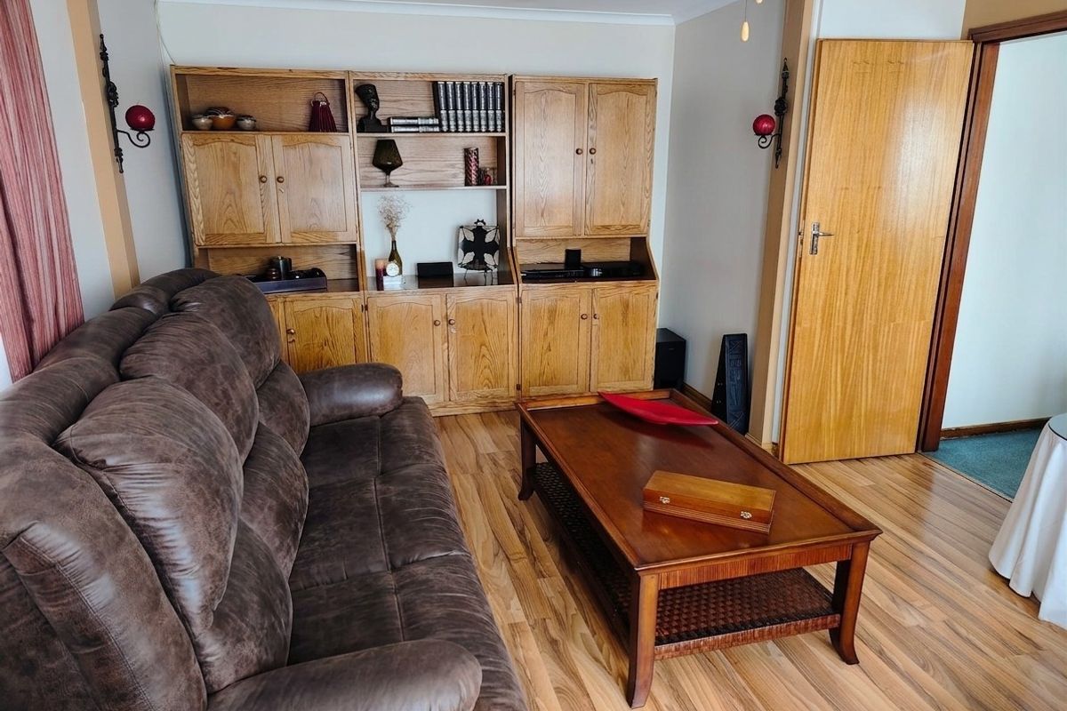 A living room featuring built-in wooden cabinetry, laminate flooring, and a classic wooden door, offering a functional and traditional layout.