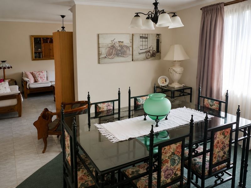 Open plan dining and living area featuring a combination of tiled and carpeted flooring with a central chandelier.
