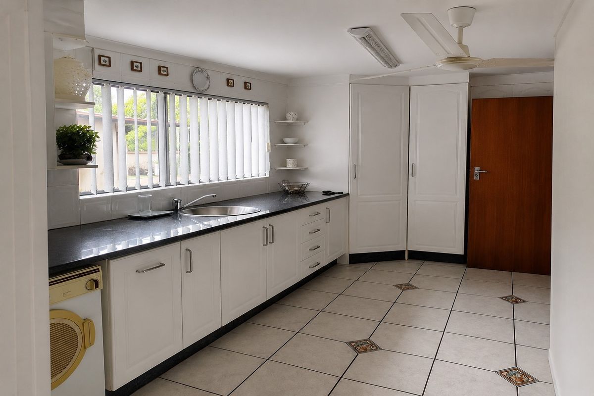 A functional kitchen featuring white cabinetry, dark granite countertops, tiled flooring, and a ceiling fan, offering ample storage and workspace.