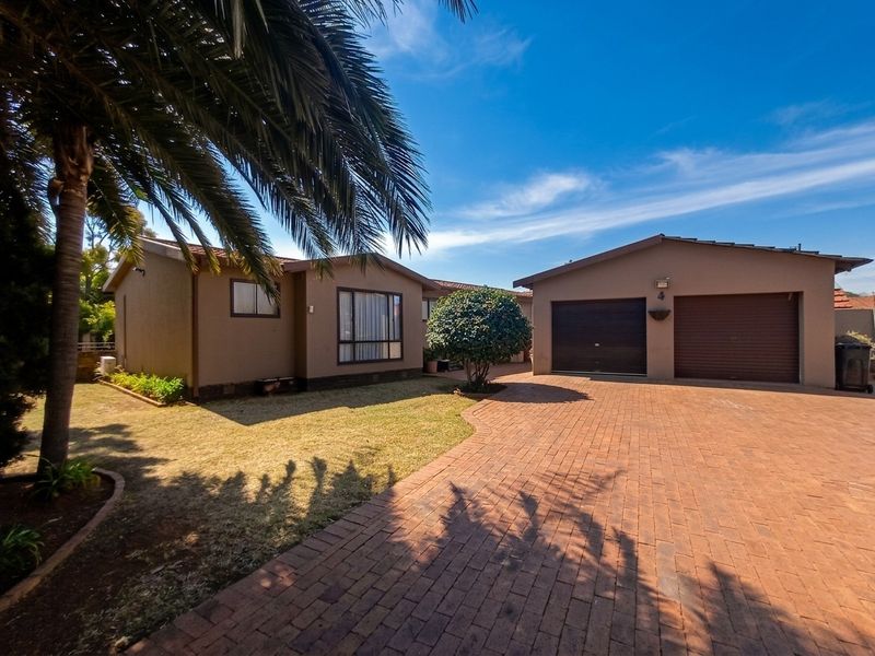 Front view of the property featuring a paved driveway, double garage, and well-maintained exterior facade with established garden.