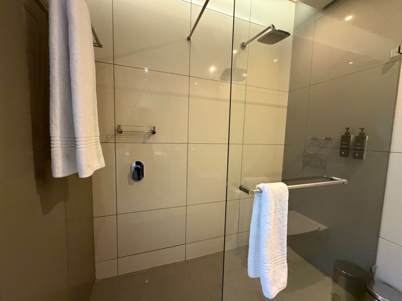Modern walk-in shower featuring large-format wall tiles, a glass enclosure, and a rainfall shower head.