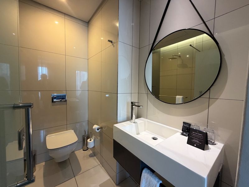 Modern bathroom featuring a floating vanity, wall-mounted toilet, and sleek tiled finishes with contemporary fixtures.