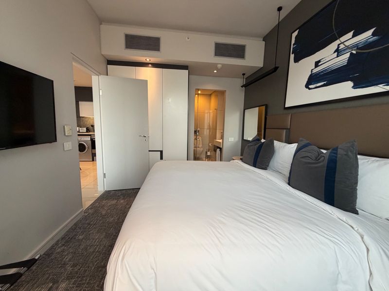 Modern bedroom featuring built-in cupboards, central air conditioning, and direct access to an en-suite bathroom.