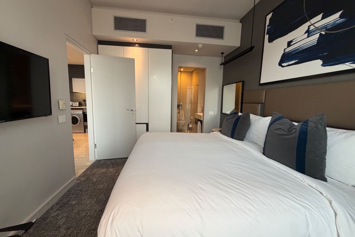 Modern bedroom featuring built-in cupboards, central air conditioning, and direct access to an en-suite bathroom.