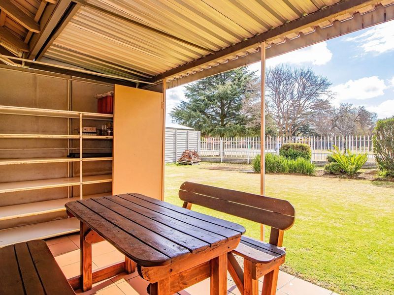Covered patio area featuring tiled flooring, a built-in storage shelving unit, and direct access to the rear garden.