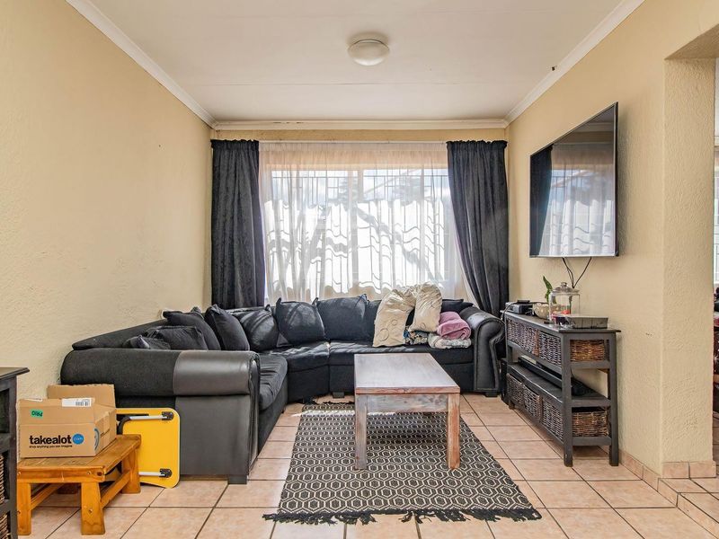 A functional living room featuring tiled flooring and neutral wall finishes, providing a comfortable and practical space for relaxation.