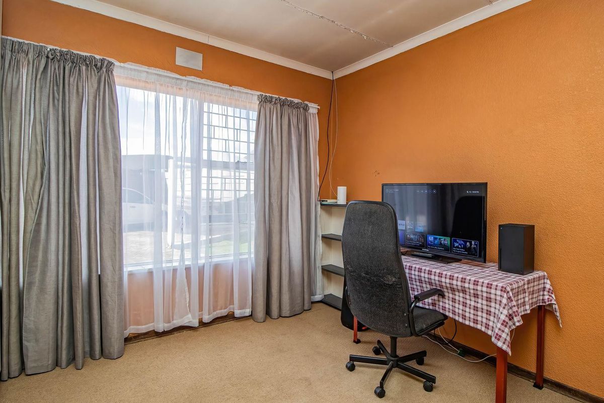 A bedroom featuring carpet flooring, a built-in wardrobe, and security bars on the window. The room requires cosmetic updates to the walls and ceiling.