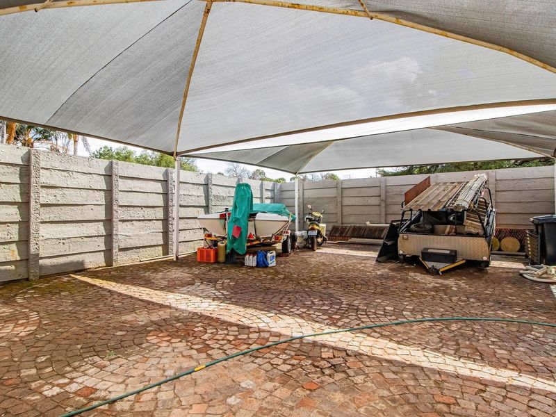 A paved outdoor area featuring a large shade sail structure and perimeter precast concrete walling, suitable for covered parking or storage.