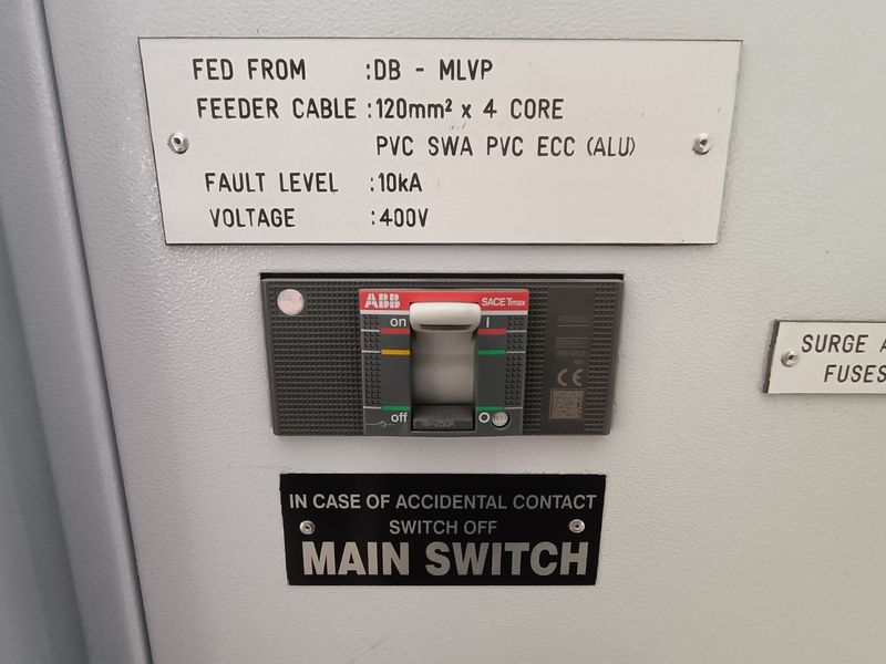 Close-up view of an industrial electrical distribution board featuring an ABB SACE Tmax circuit breaker and technical specification labeling.