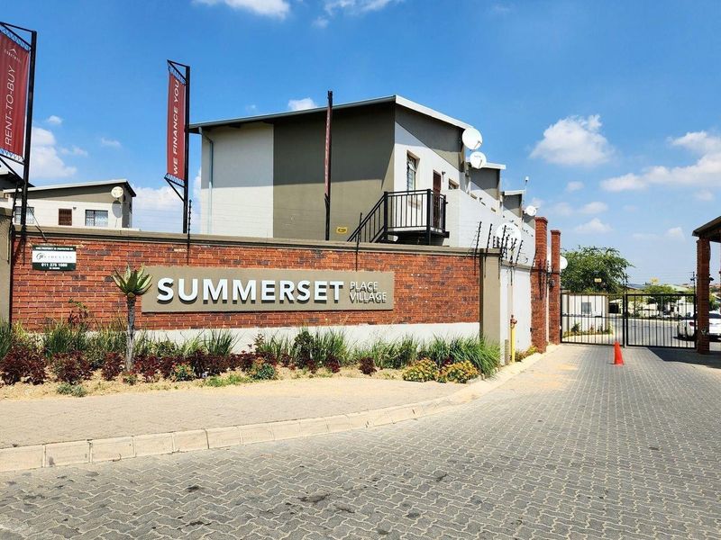 The entrance to Summerset Place Village featuring a brick boundary wall, electric fencing, and a secure gated access point.