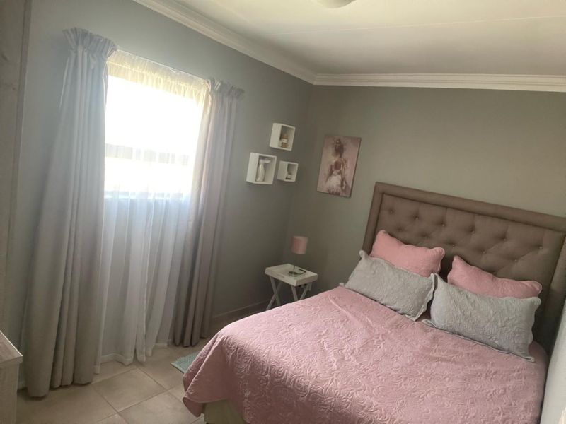A bedroom featuring tiled flooring, neutral wall paint, and coving detail around the ceiling perimeter.