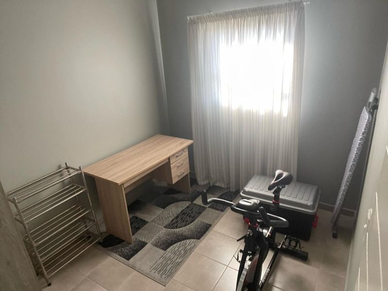 A functional bedroom space featuring neutral wall tones and tiled flooring, suitable for use as a home office or guest room.