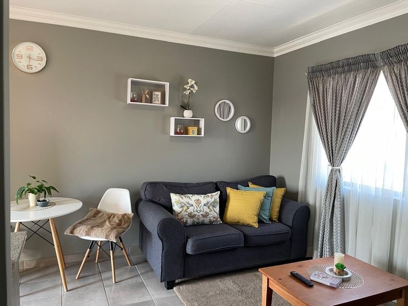 A cozy living room featuring neutral grey walls, crown molding, and tiled flooring, providing a comfortable and well-maintained living space.