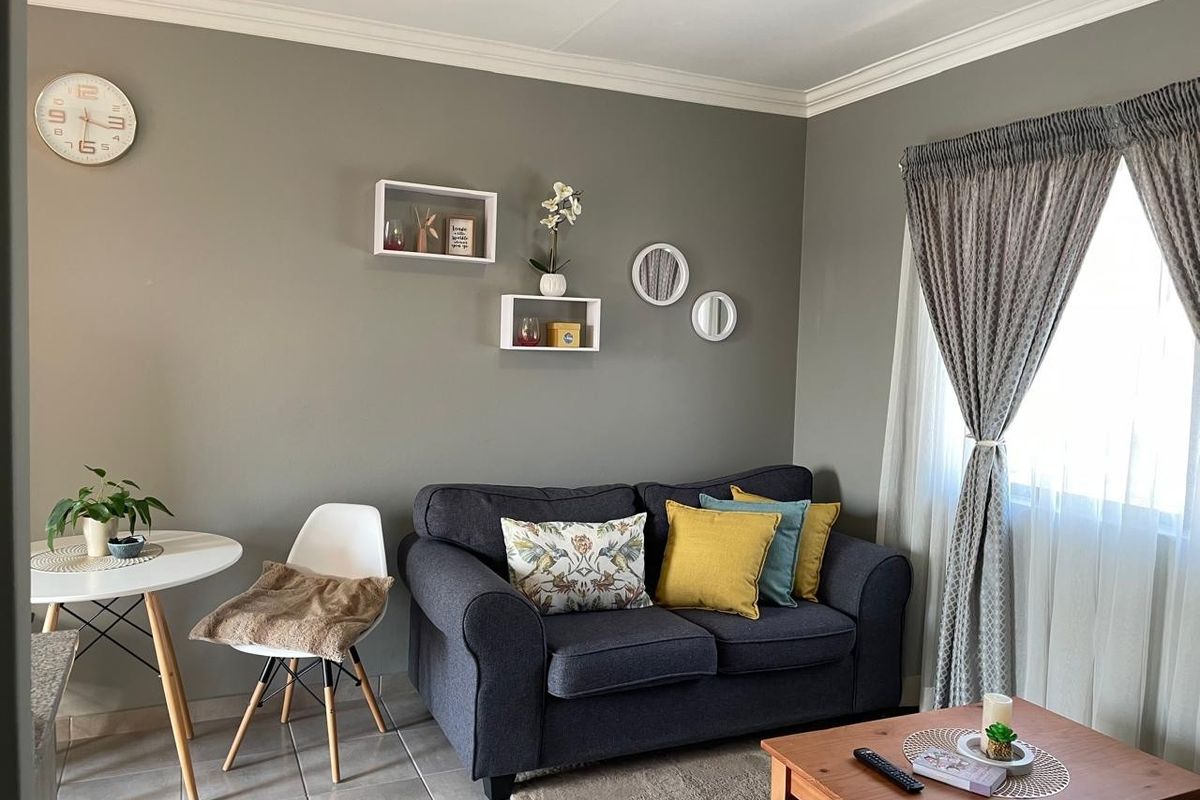 A cozy living room featuring neutral grey walls, crown molding, and tiled flooring, providing a comfortable and well-maintained living space.