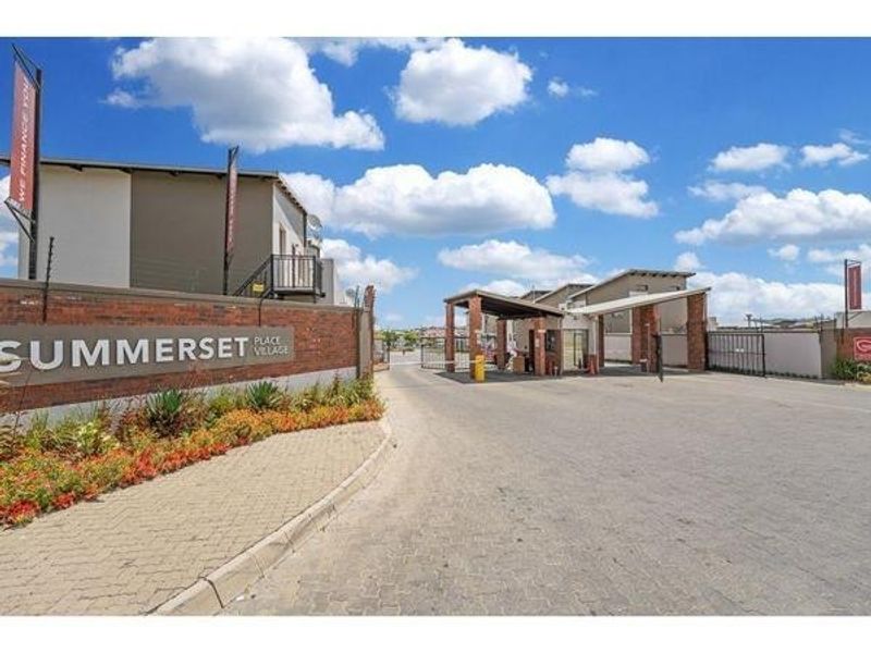 The entrance to Summerset Place Village featuring a secure gated access point, brick boundary wall, and paved driveway.
