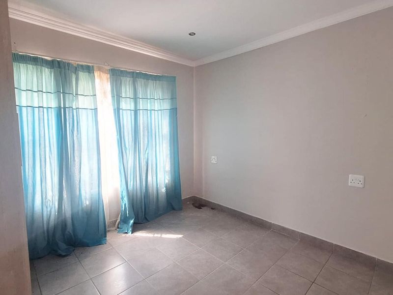 An empty bedroom featuring tiled flooring, coved ceilings, and neutral wall finishes, providing a blank canvas for personalization.