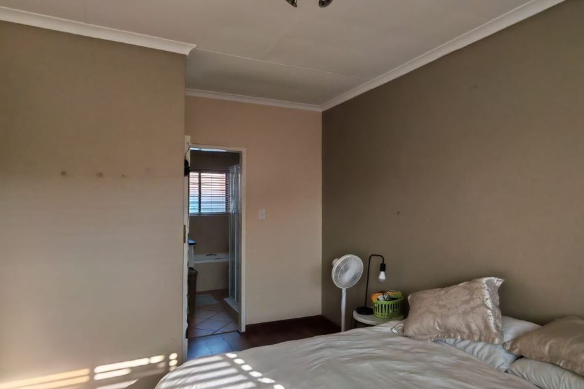 A bedroom featuring laminate flooring, neutral wall tones, and direct access to an en-suite bathroom.
