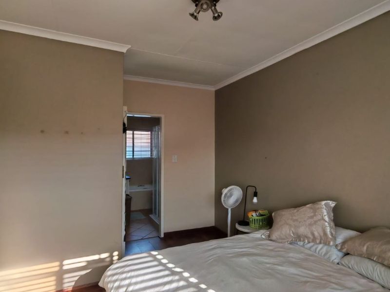 A bedroom featuring laminate flooring, neutral wall tones, and direct access to an en-suite bathroom.