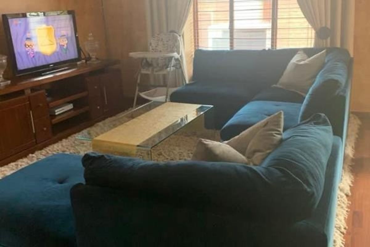 A comfortable living room featuring hardwood flooring and venetian blinds, providing a functional space for relaxation.