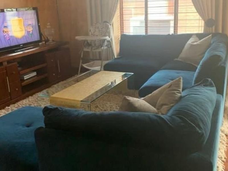 A comfortable living room featuring hardwood flooring and venetian blinds, providing a functional space for relaxation.