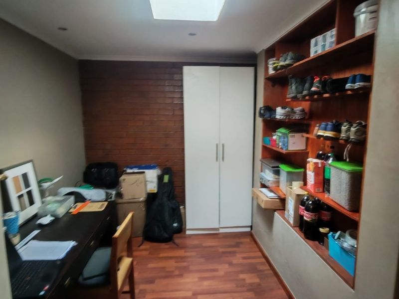 A functional office space featuring built-in shelving, a built-in wardrobe, laminate flooring, and an exposed brick feature wall.