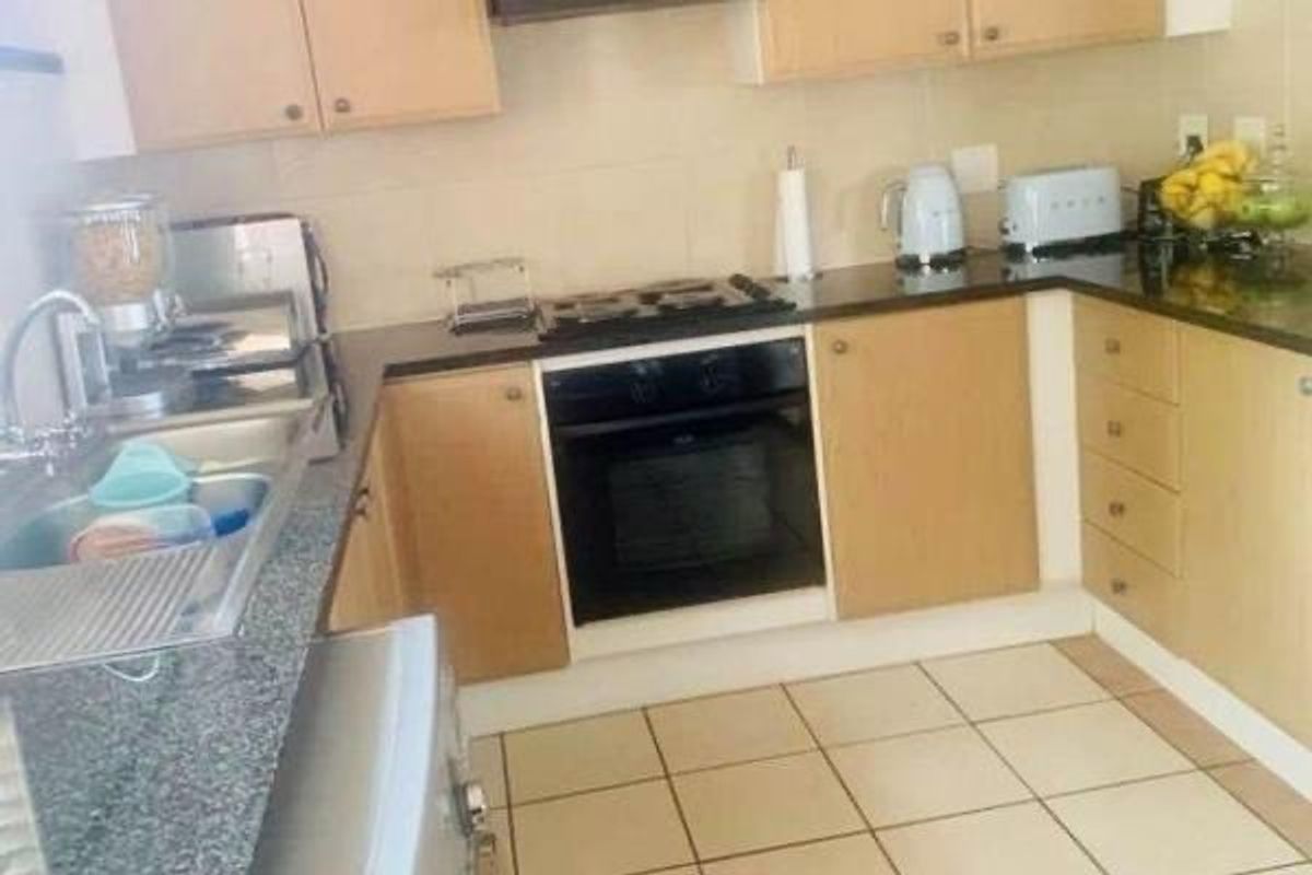 A functional kitchen featuring light wood cabinetry, granite countertops, a built-in oven with gas hob, and tiled flooring.
