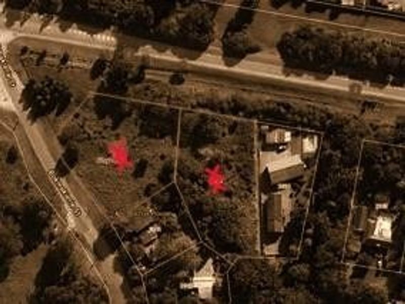 Aerial view of residential vacant land parcels with marked boundaries, showing surrounding street access and existing neighboring structures.