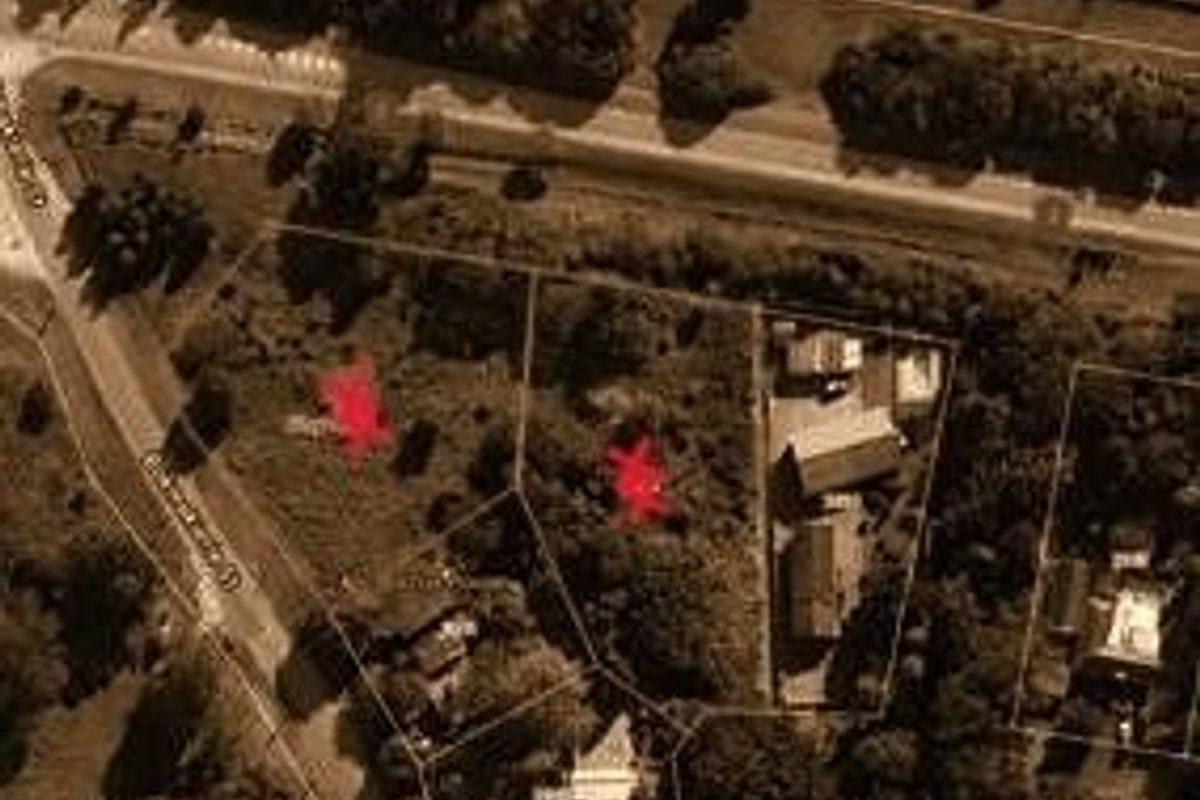Aerial view of residential vacant land parcels with marked boundaries, showing surrounding street access and existing neighboring structures.