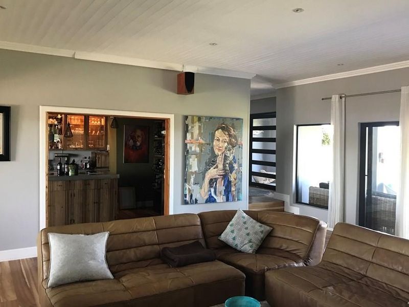Spacious living room featuring timber flooring, recessed lighting, and a view into an adjacent built-in bar area with wooden cabinetry.
