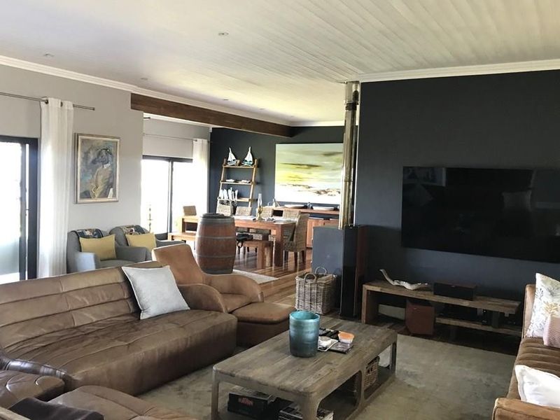 Spacious open-plan living and dining area featuring a modern wood-burning fireplace, exposed timber ceiling beams, and large sliding doors providing natural light.