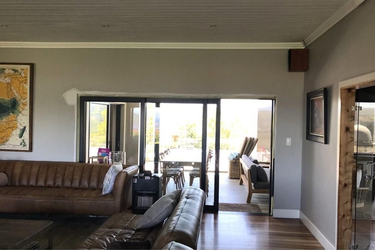 Spacious living room featuring timber flooring, crown molding, and large sliding glass doors that open onto an outdoor patio area.