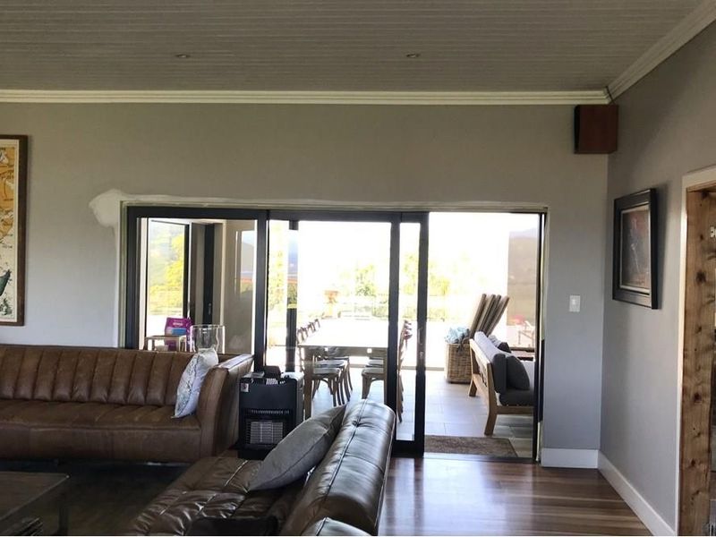 Spacious living room featuring timber flooring, crown molding, and large sliding glass doors that open onto an outdoor patio area.