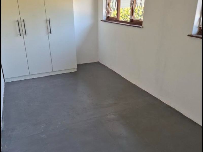 A clean, empty bedroom featuring built-in wardrobes, painted walls, and security gates on the windows.