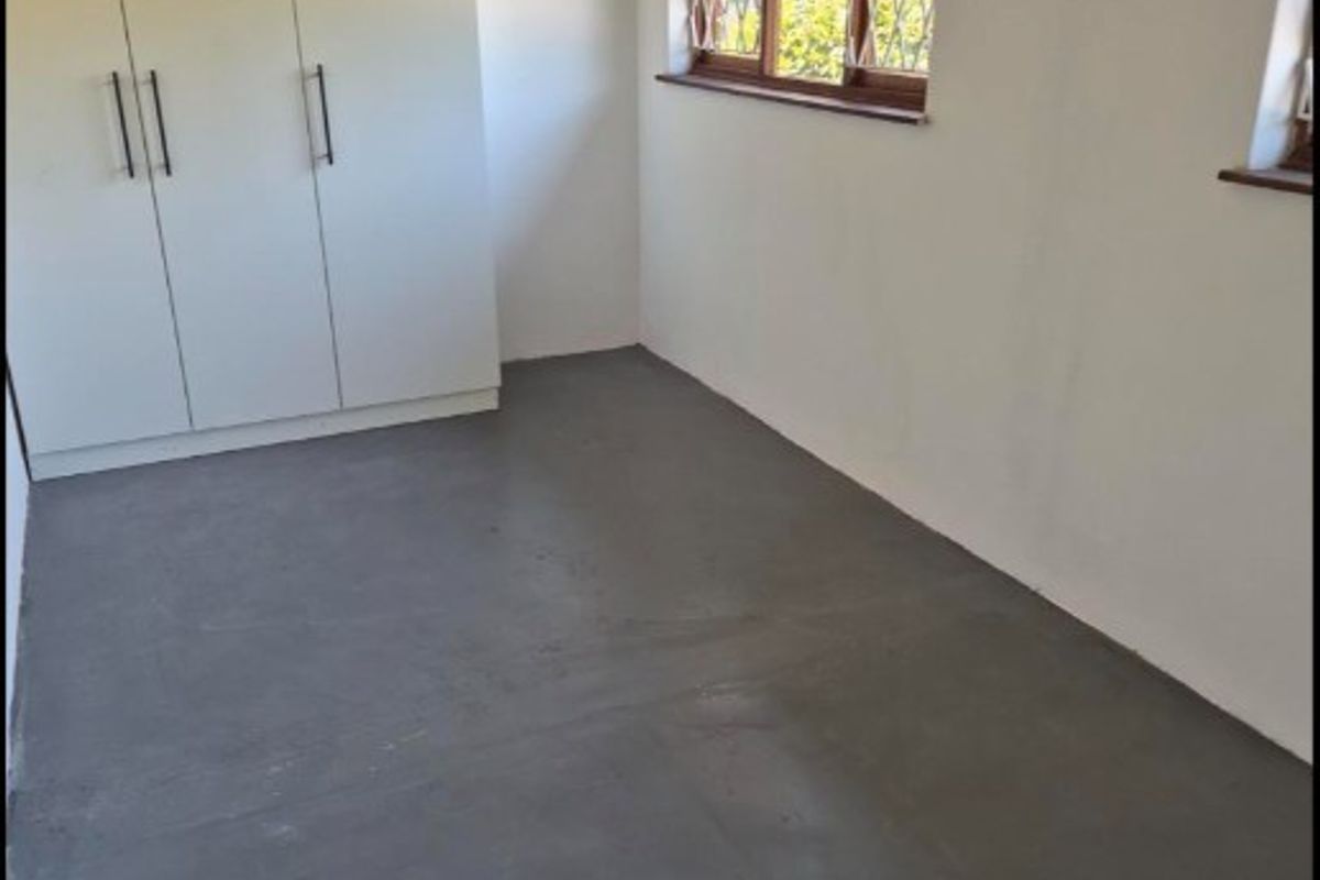 A clean, empty bedroom featuring built-in wardrobes, painted walls, and security gates on the windows.