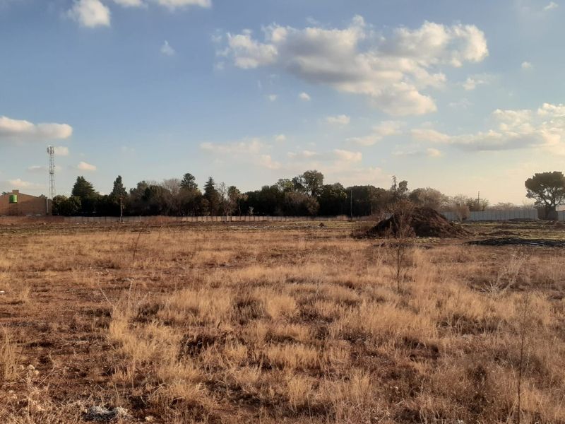 A large, undeveloped plot of land featuring dry grass and perimeter fencing, offering significant potential for future development or landscaping.